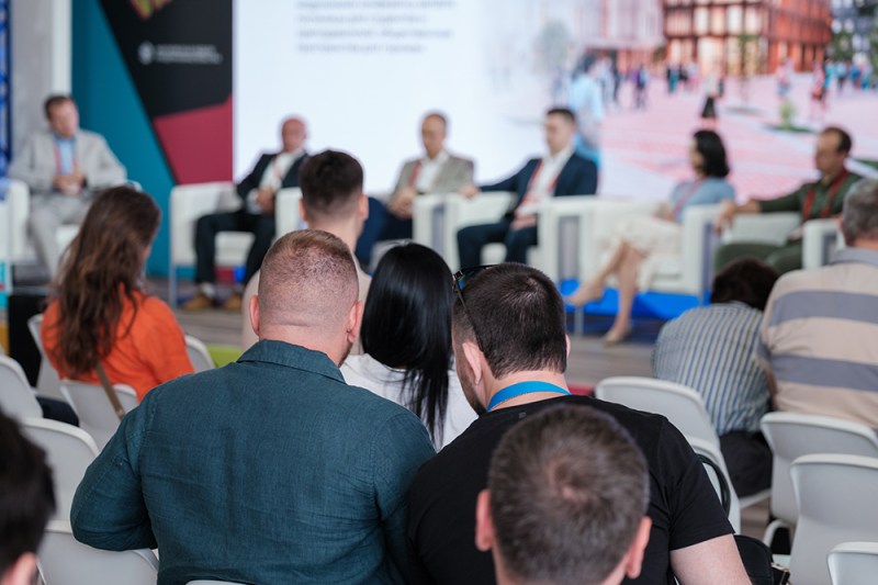 People attending conference focusing on expert panel discussion with speakers sharing knowledge and insights.