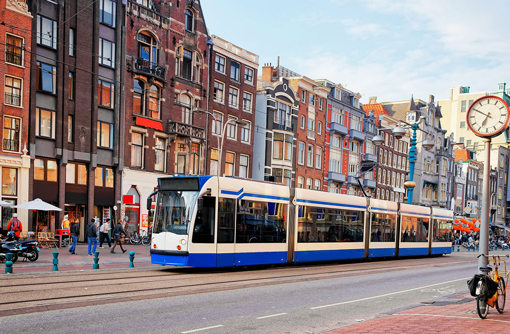 Public-tram-crossing-Damrak-main-street-crowded-with-tourists-Amsterdam